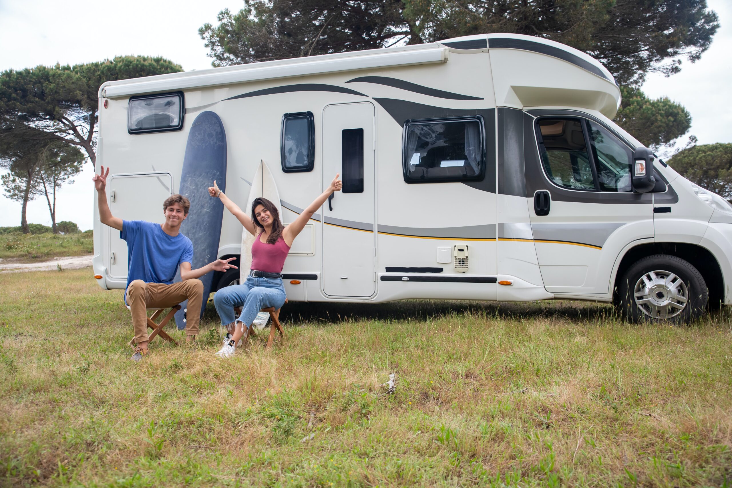 man and woman sitting outside rv with hands up